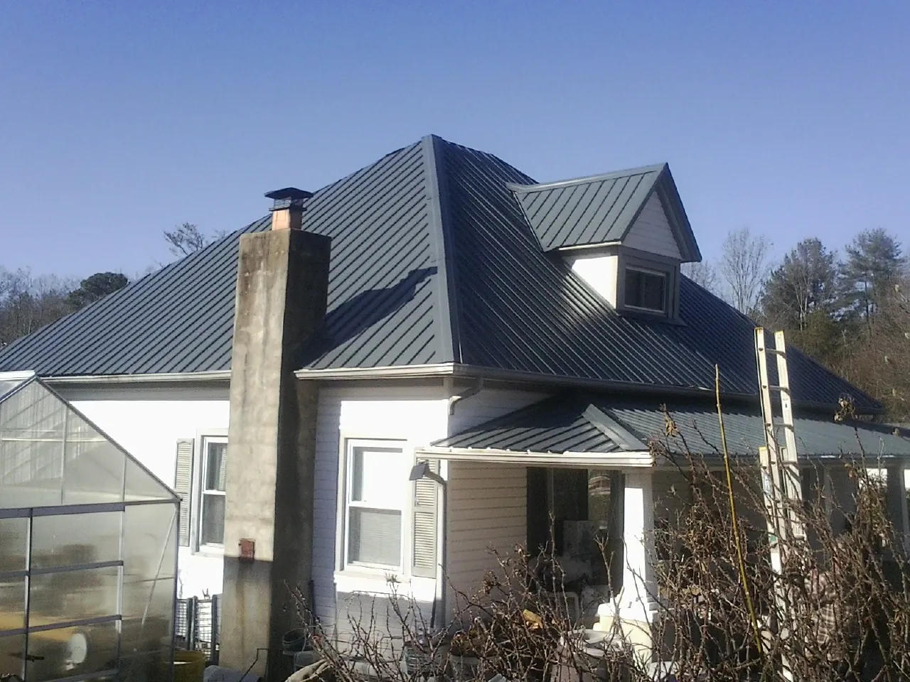 Dark blue standing seam metal roof on a white farmhouse with dormer — Slate & Tile Roof Repair by Roofing Brothers in Canal Fulton