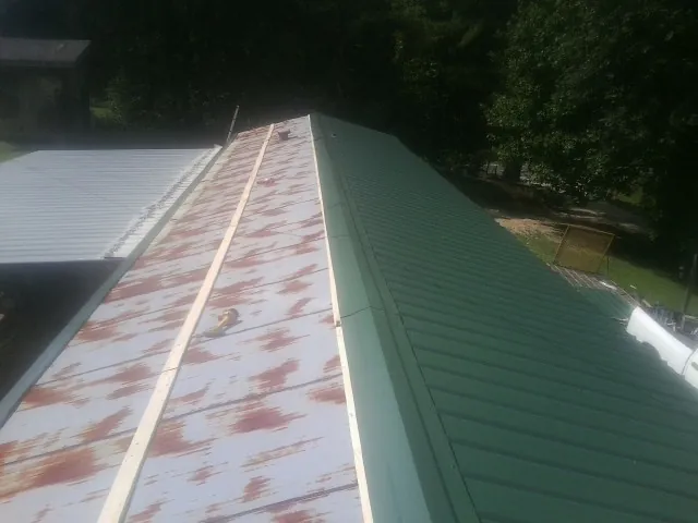 Old rusted panels beside newly installed green metal roofing — Wind Damage Roof Repair by Roofing Brothers in Canal Fulton