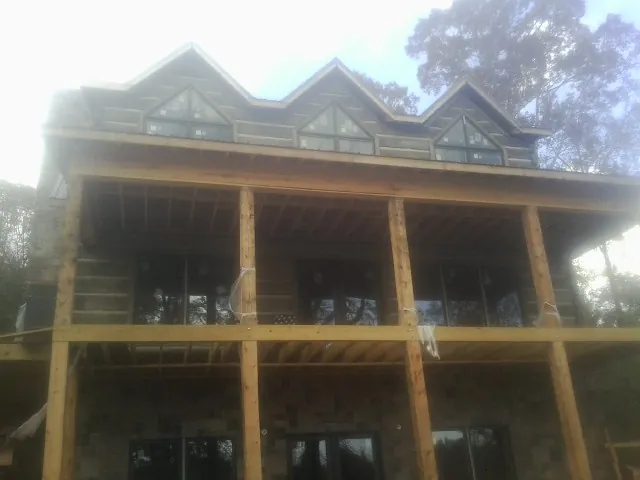 Dormers and porch framing on a large log home under construction — Roof Coating work by our crew in Canal Fulton