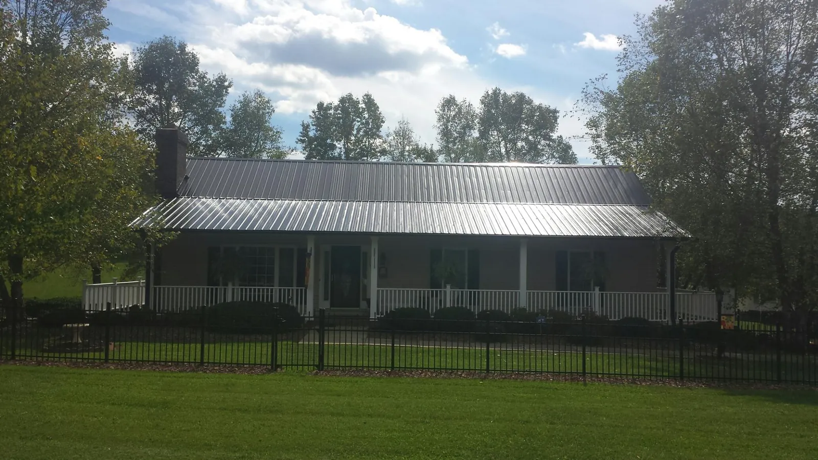 Gray metal roof on a brick ranch with a full width front porch — Gutter Guard Installation work by our crew in Canal Fulton