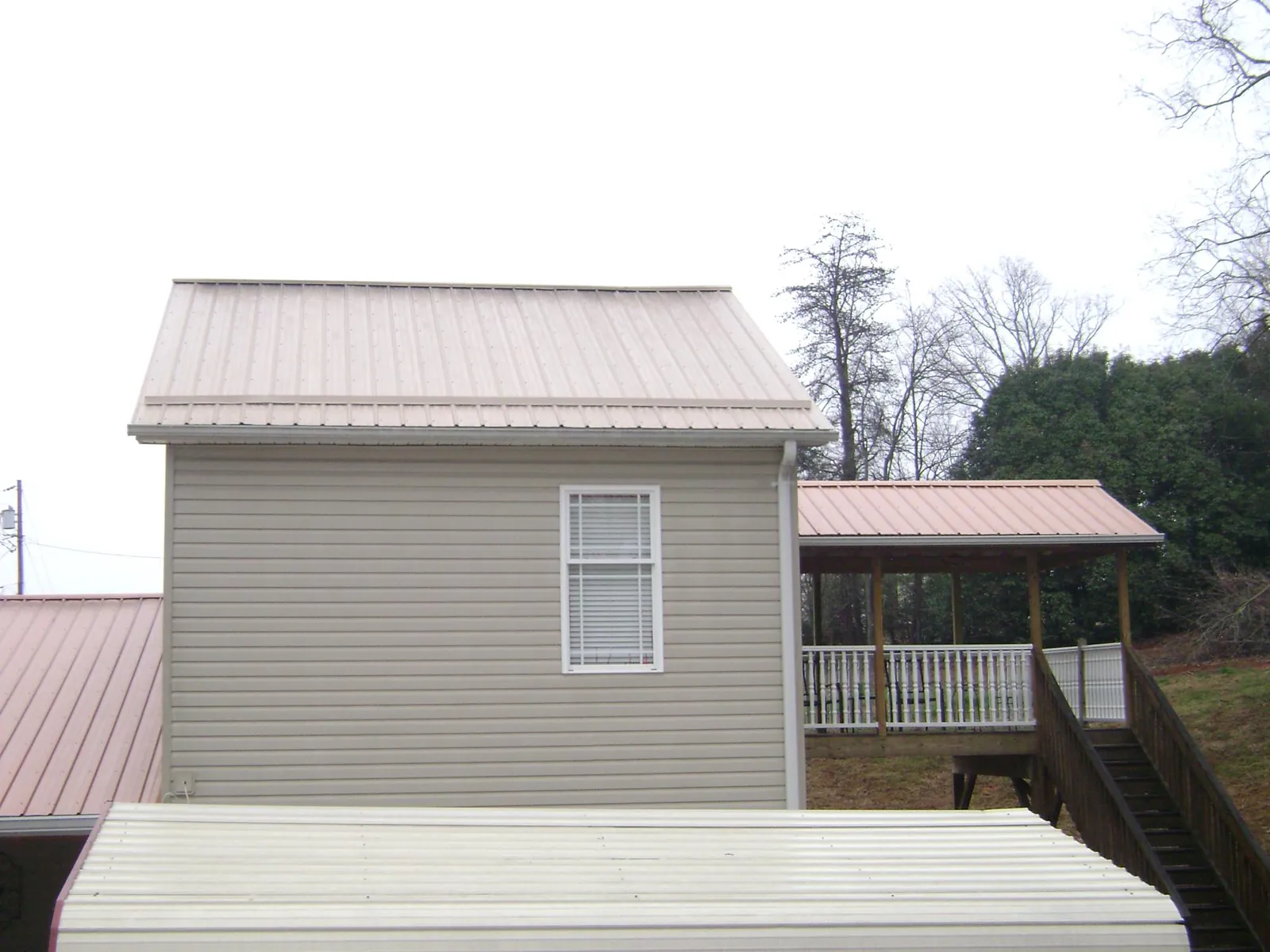 Tan metal roofs on a two story addition and attached porch, from a Roof Replacement job in Canal Fulton