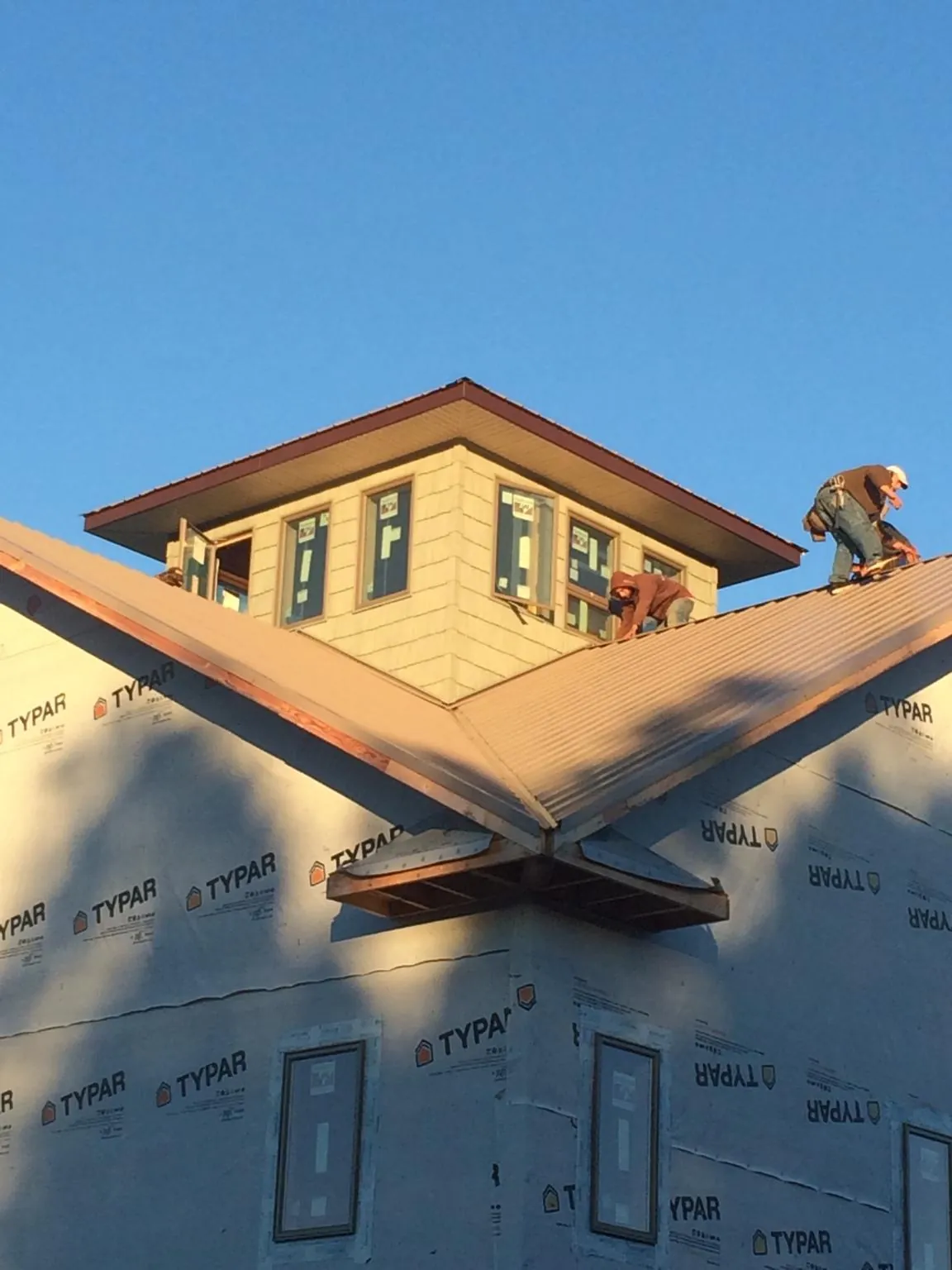 Roofers working around a rooftop cupola on a new metal roof at sunset — Roof Waterproofing in Canal Fulton by Roofing Brothers